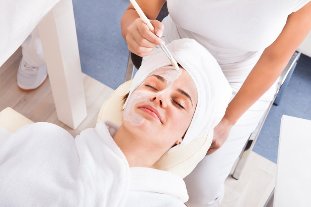 A beautician applies a mask to the face